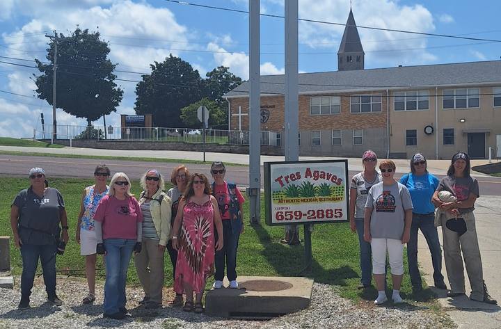 A group of riders standing by the Tres Agaves restaurant sign