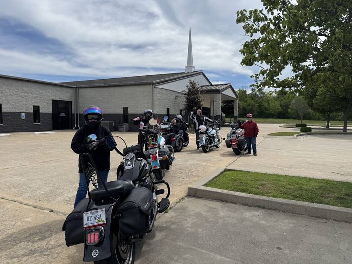 Riders with their motorcycles in a church parking lot
