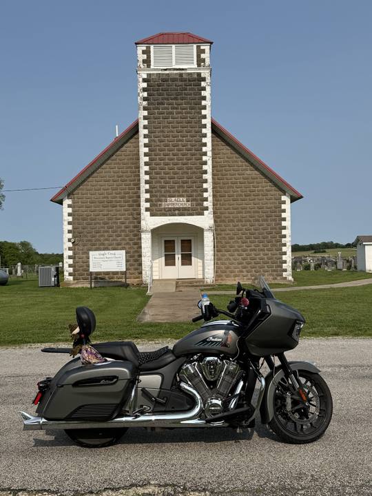A motorcycle parked in front of a small stone church