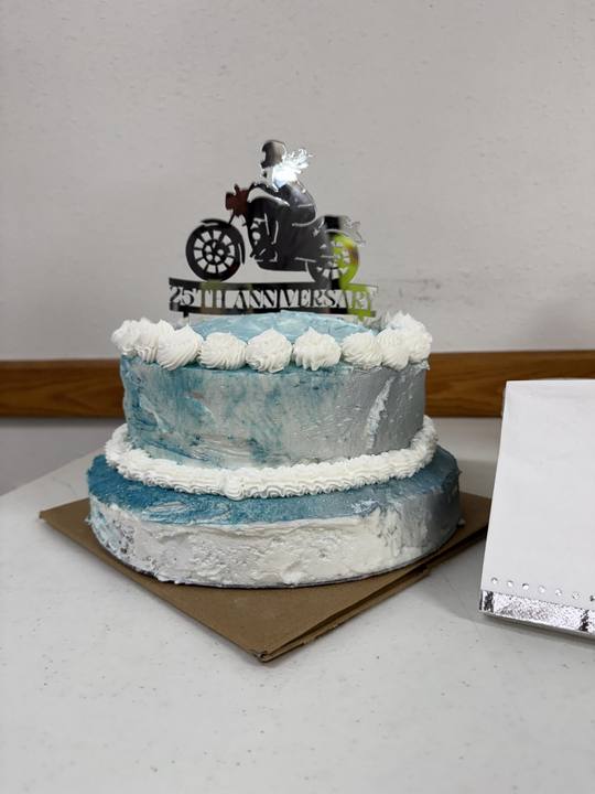 A white anniversary cake topped with a small motorcycle
