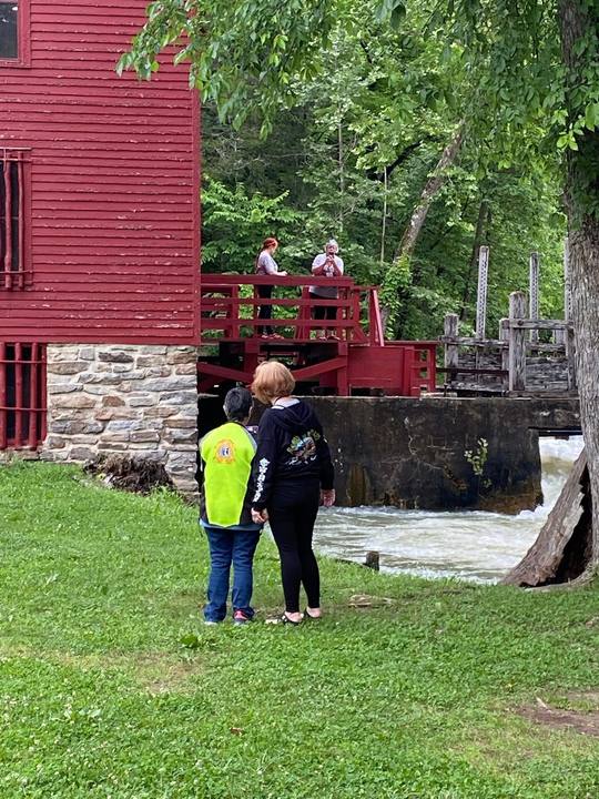 A rider looking at a red mill beside a waterfall